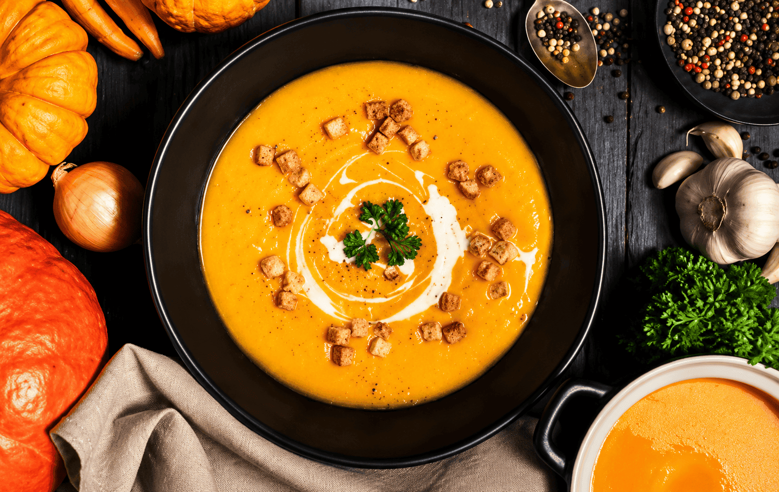 Autumn harvest soup with spices and pumpkins in the background