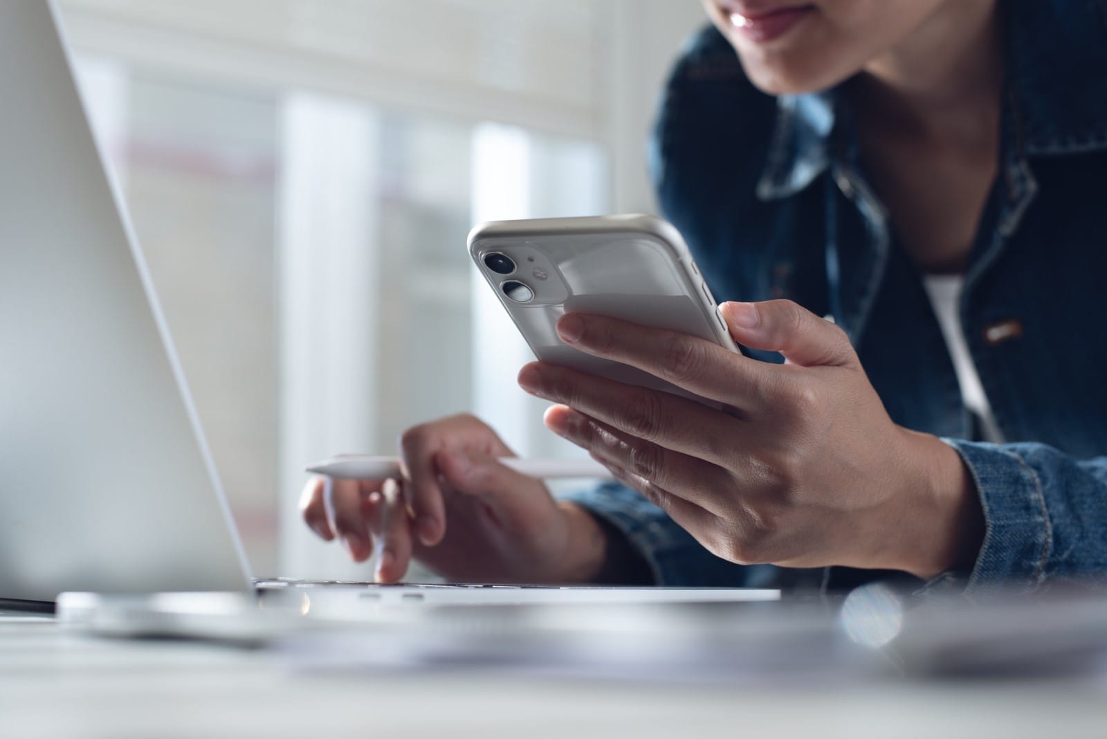 Person holding a mobile phone and typing on a keyboard