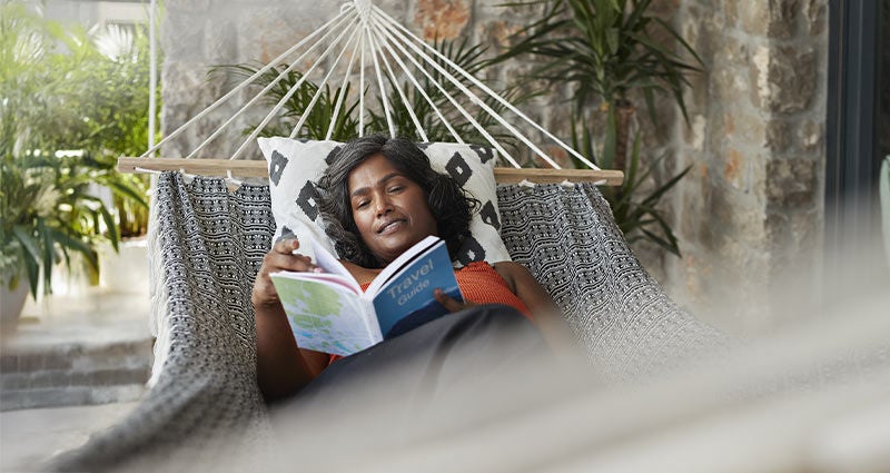 Brown woman reclining on a hammock. 