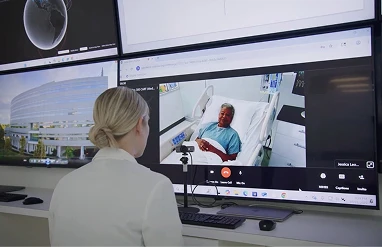 Nurse sitting at a desk watching multiple patients on a monitor
