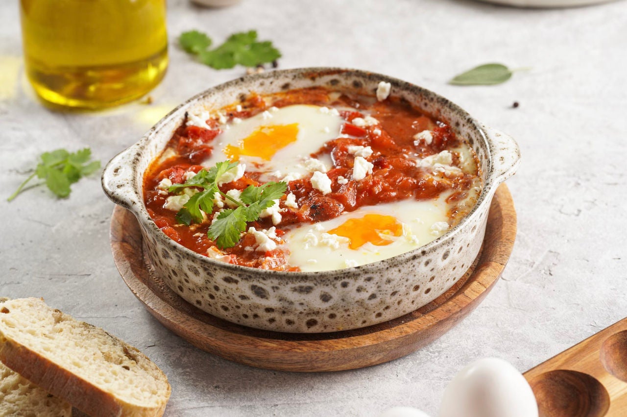 Bowl of red sauce with two fried eggs.