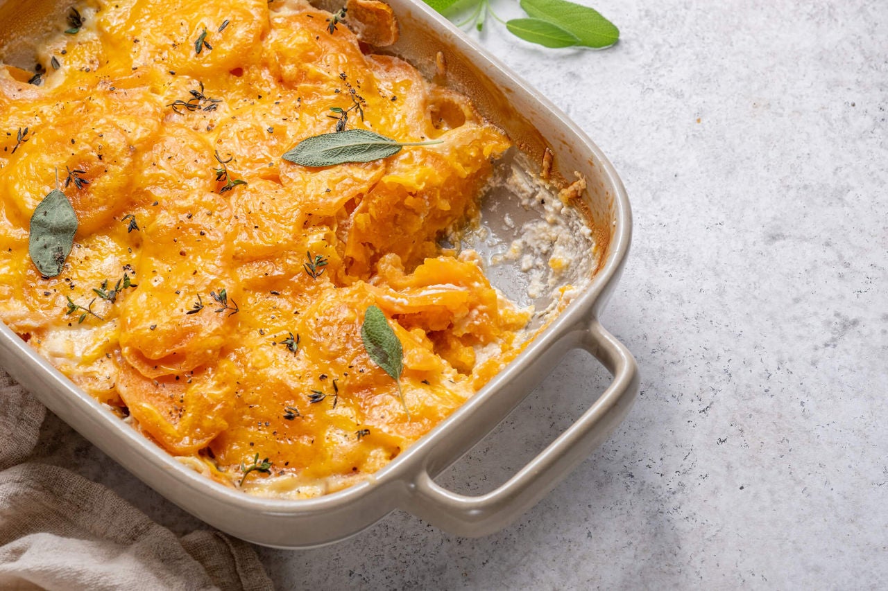 Casserole with sliced rutabaga and butternut squash baked under layer of cheese. 