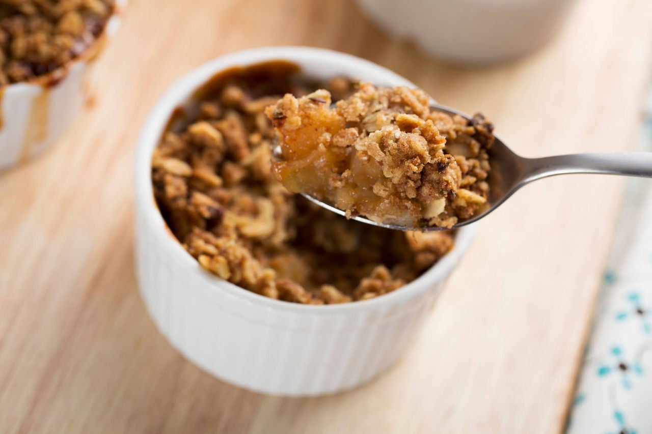 Pear crumble on a spoon over a ramekin with more pear crumble.