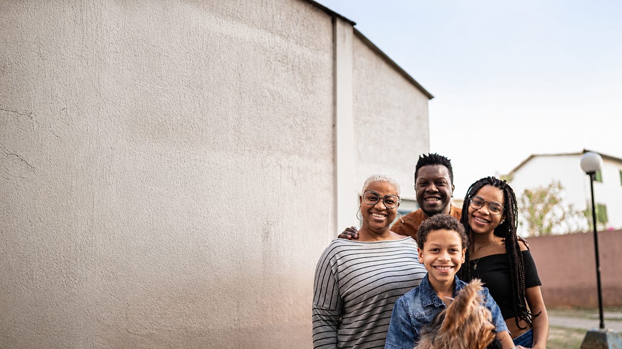Multi-generational family standing together outdoors, smiling.