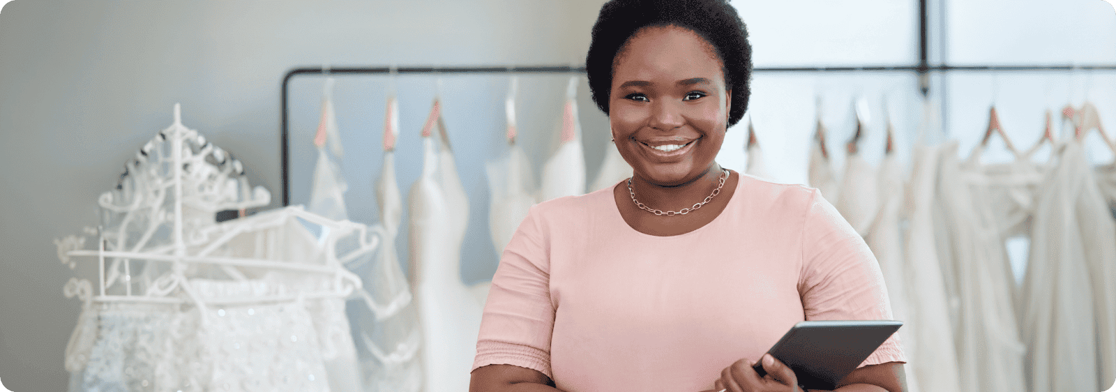 Portrait of a young seamstress standing with a tablet in her boutique