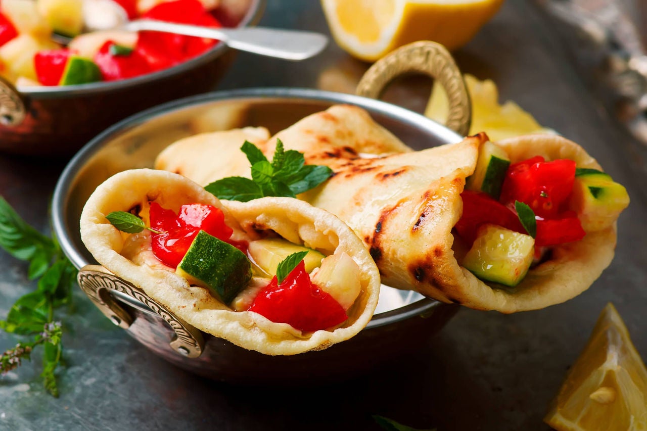 Whole wheat wrap filled with lettuce, tomato, cucumber, and grilled meat