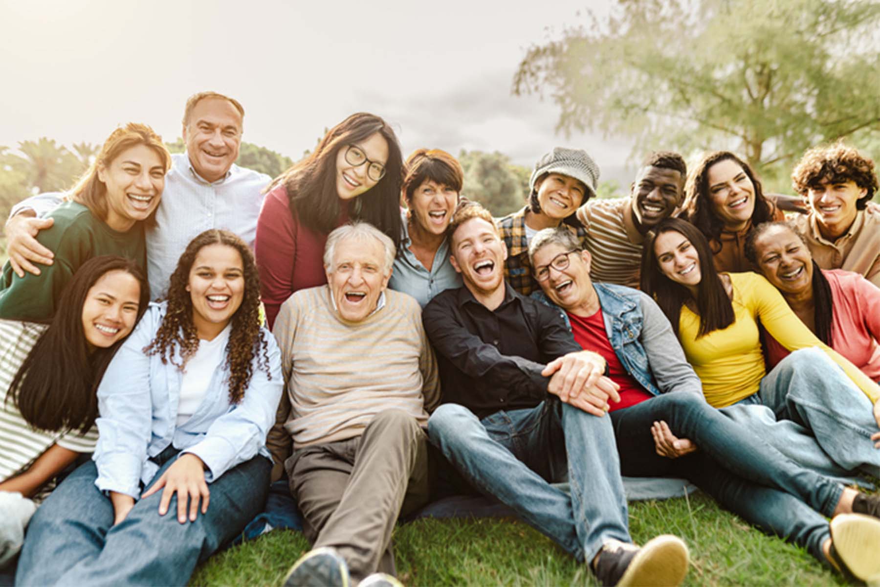Group of diverse people of different ages smiling and laughing together outdoors.