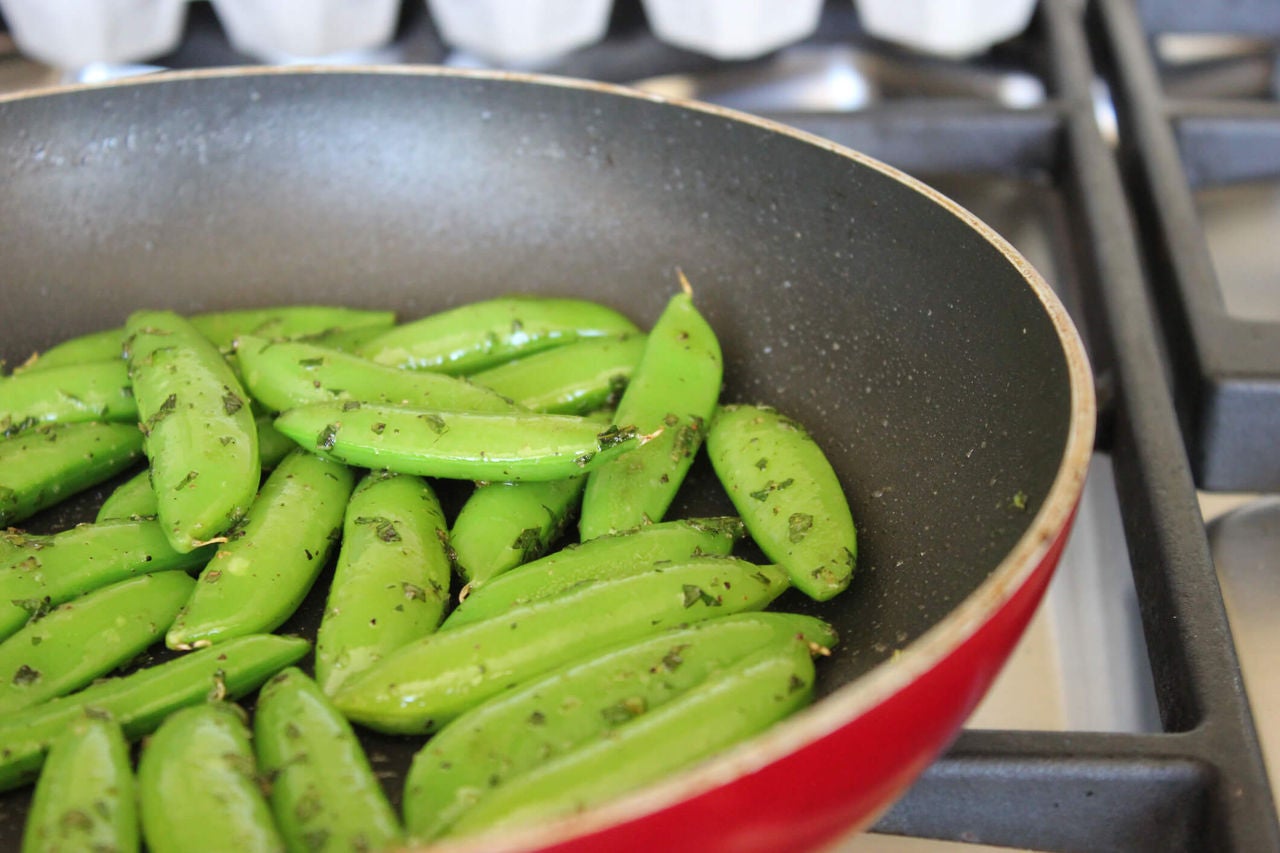 Buttered snap peas in a pan.