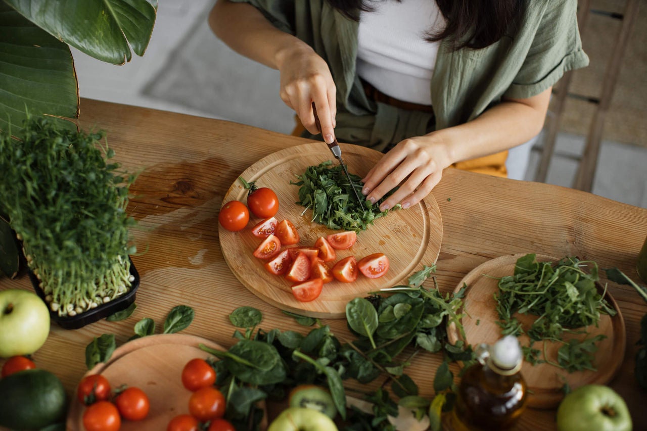 Woman chopping tomatoes and other salad ingredients.
