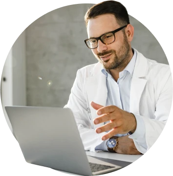 Male doctor wearing glasses having a virtual consultation on a laptop.