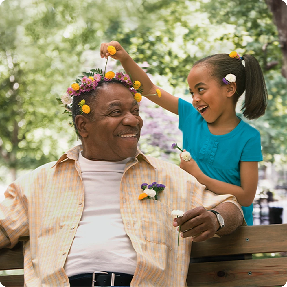  Man and child outdoors smiling together in a park during springtime, wearing flowers in their hair.