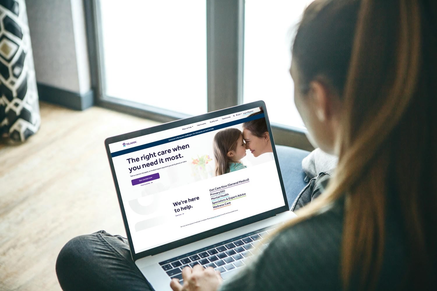 Person sitting at home using a laptop to access the Teladoc Health website for online medical care.