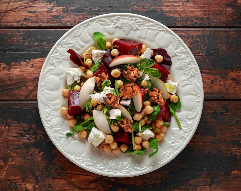 Healthy Beet Salad with chickpeas, pistachios nuts, feta cheese on rustic wooden background.