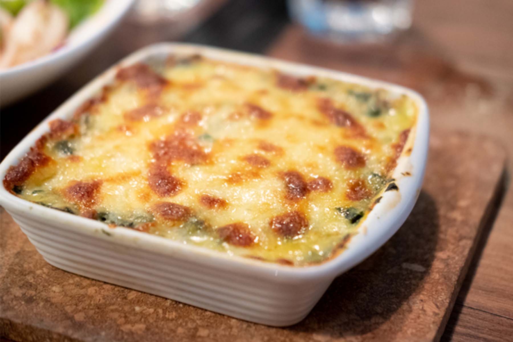 Baked egg and vegetable casserole in a white dish on a wooden surface