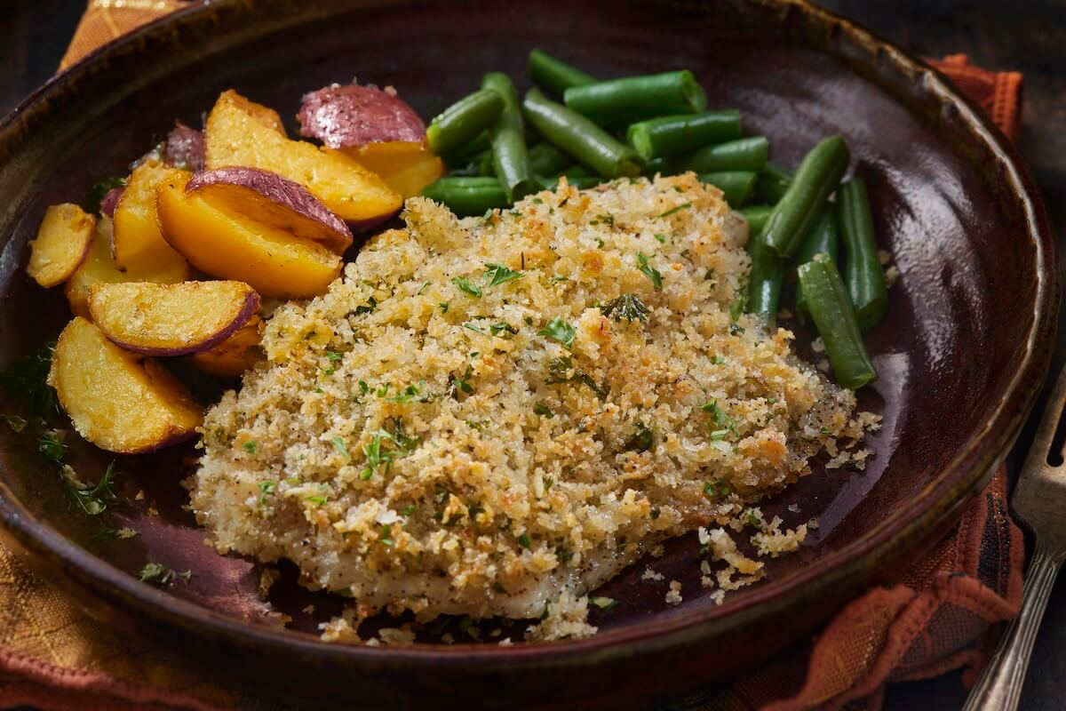Pan with parmesan crusted chicken breast, potatoes, and green beans.