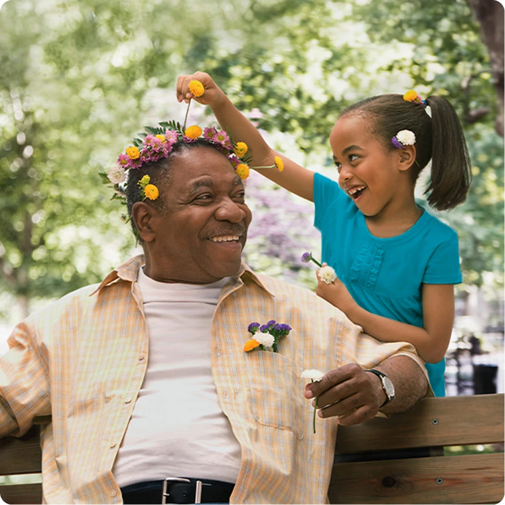  Man and child outdoors smiling together in a park during springtime, wearing flowers in their hair.