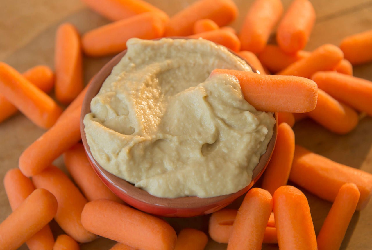 Baby carrots and a small bowl of plain hummus.