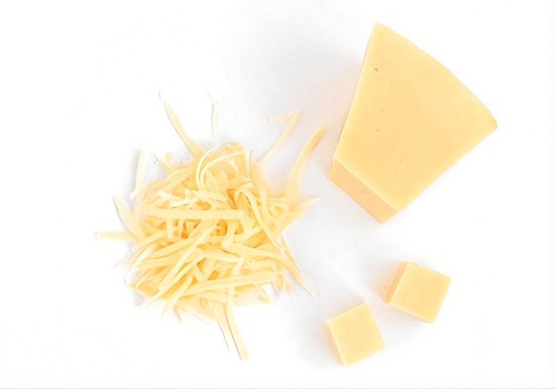 One large block and two small blocks of parmesan cheese next to a pile of shredded parmesan cheese.