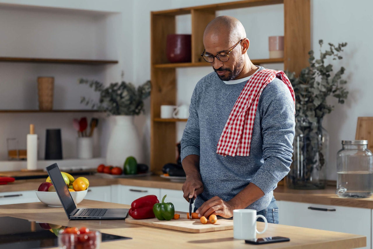 Man chopping vegetables in a brightly lit kitchen.