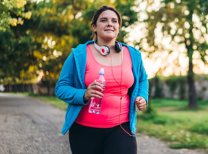 Woman in exercise clothes holding a water bottle while exercising