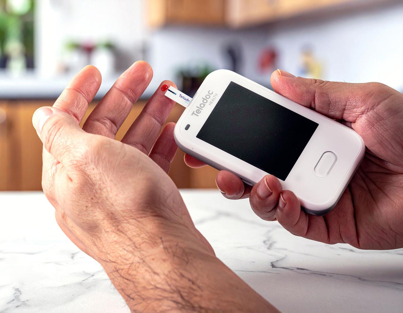 Person checking glucose levels with a glucometer at a marble counter.