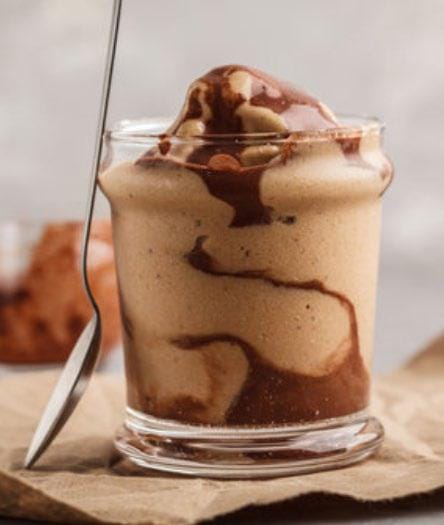 Chocolate dairy-free ice cream in a glass on a brown napkin with a spoon resting against it
