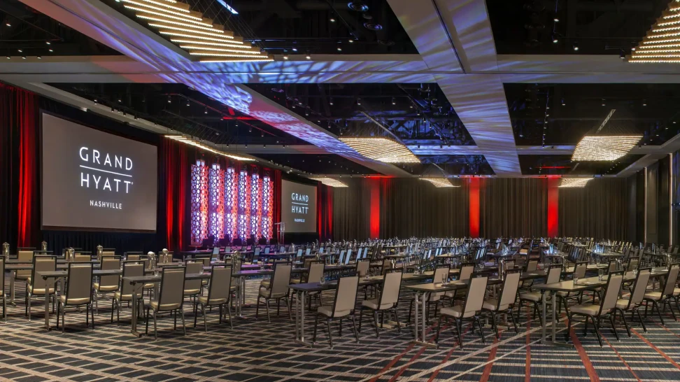 Large conference room at the Grand Hyatt set up with rows of chairs and large projection screens.