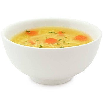 White bowl filled with chicken noodle soup, containing thin noodles, sliced carrots, and chopped green herbs, isolated on a white background.