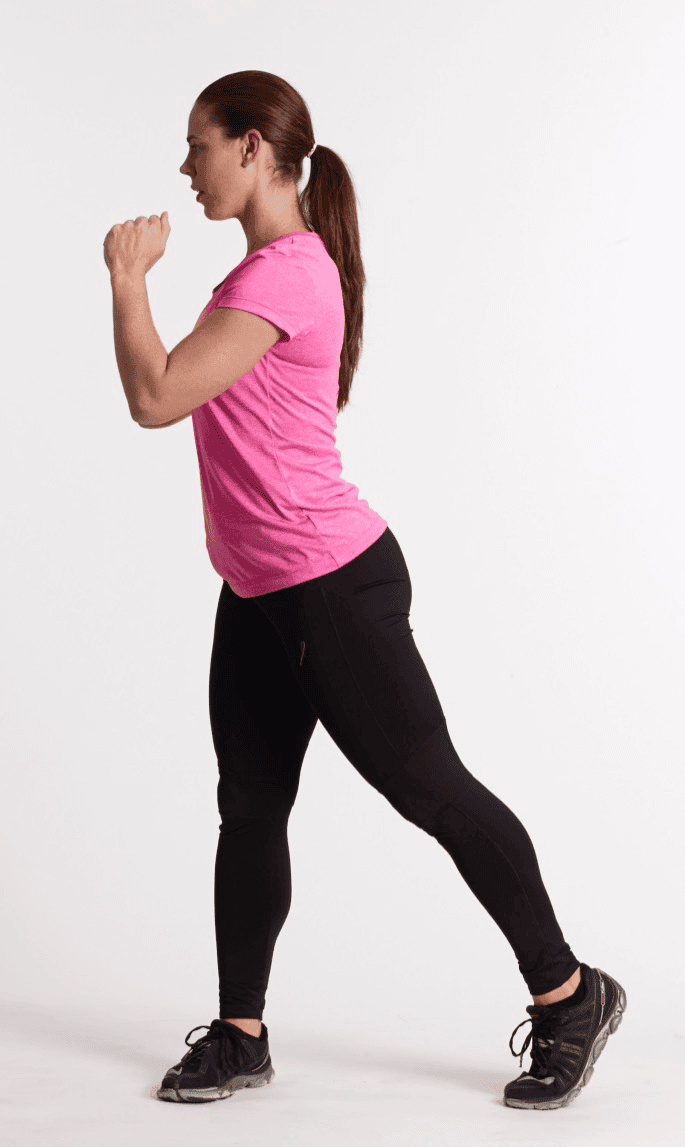 Mujer de perfil vistiendo camiseta rosa y leggings negros, en posición de estocada con una pierna extendida hacia atrás y los brazos flexionados, sobre un fondo blanco.