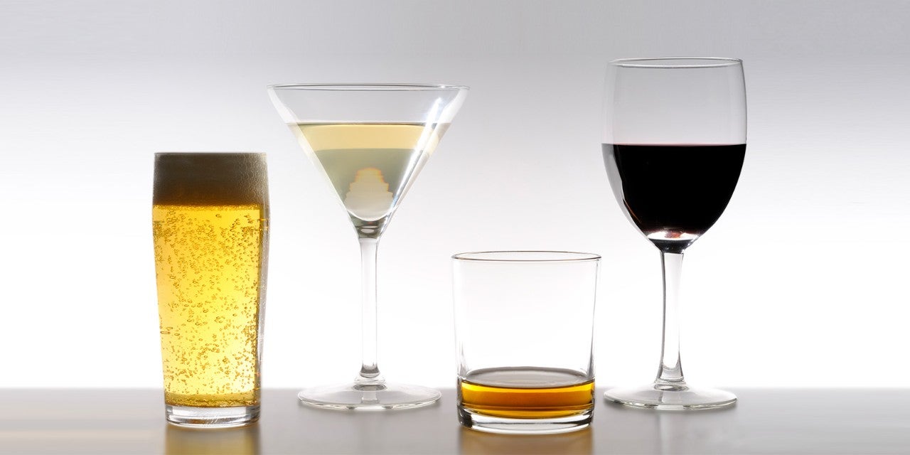 Four glasses with different beverages: a tall beer glass, a martini glass with white liquid, a short glass with amber liquid, and a wine glass with red wine.