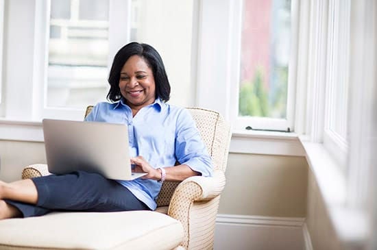 Woman sitting in chair with legs up using a laptop