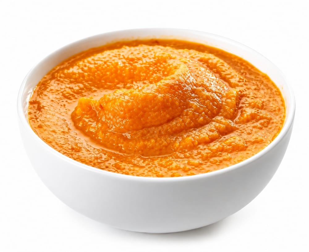 Pumpkin puree in a white bowl on a white background.