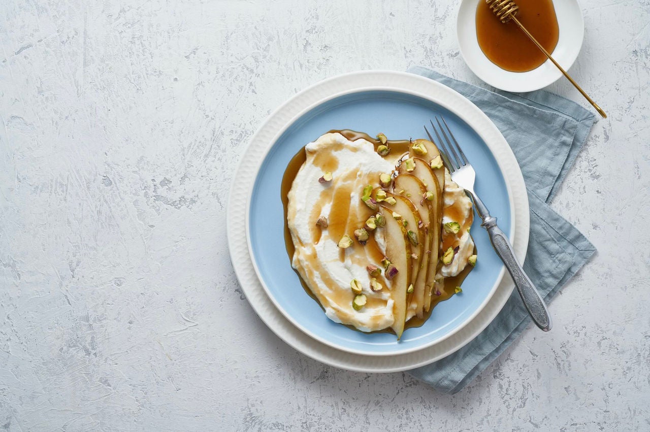 Plate with ricotta, slices of pear and honey.