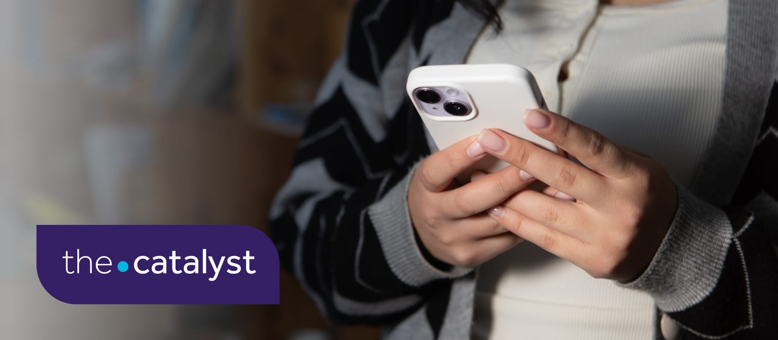 Person holding a mobile phone in their hands with the words 'the catalyst' in the bottom left.