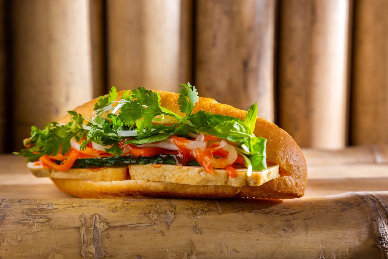 Sandwich with cilantro, onions, peppers and slabs of tofu.