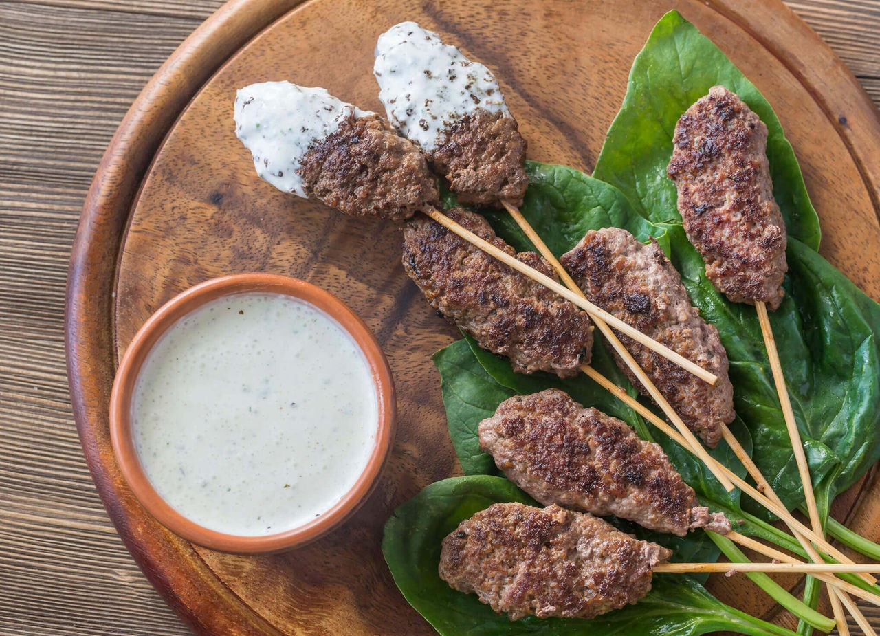 Grilled beef skewers served with tzatziki sauce and fresh greens