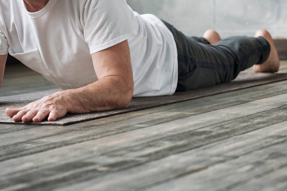 Yoga man in Cobra or sphinx pose bhujangasana variation in the gym. No face view.