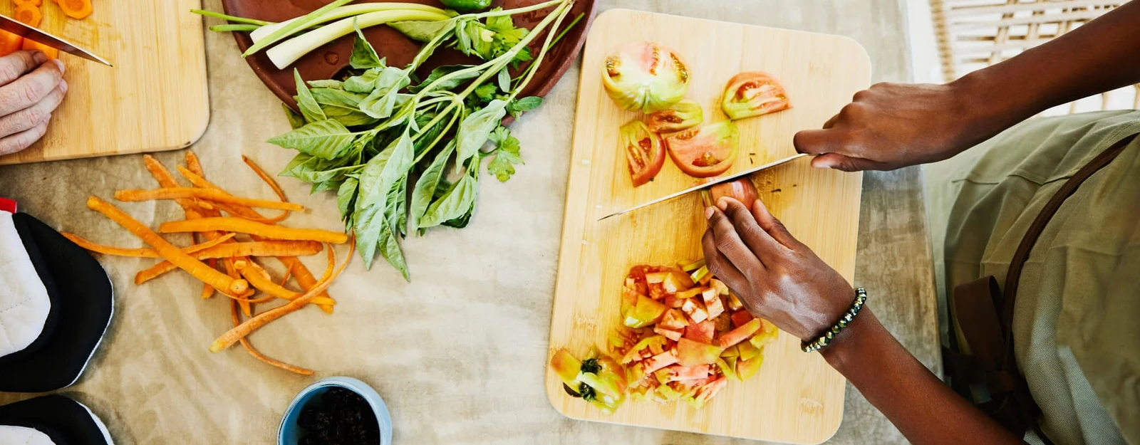 Overhead view of a person chopping vegetables on a colorful table.