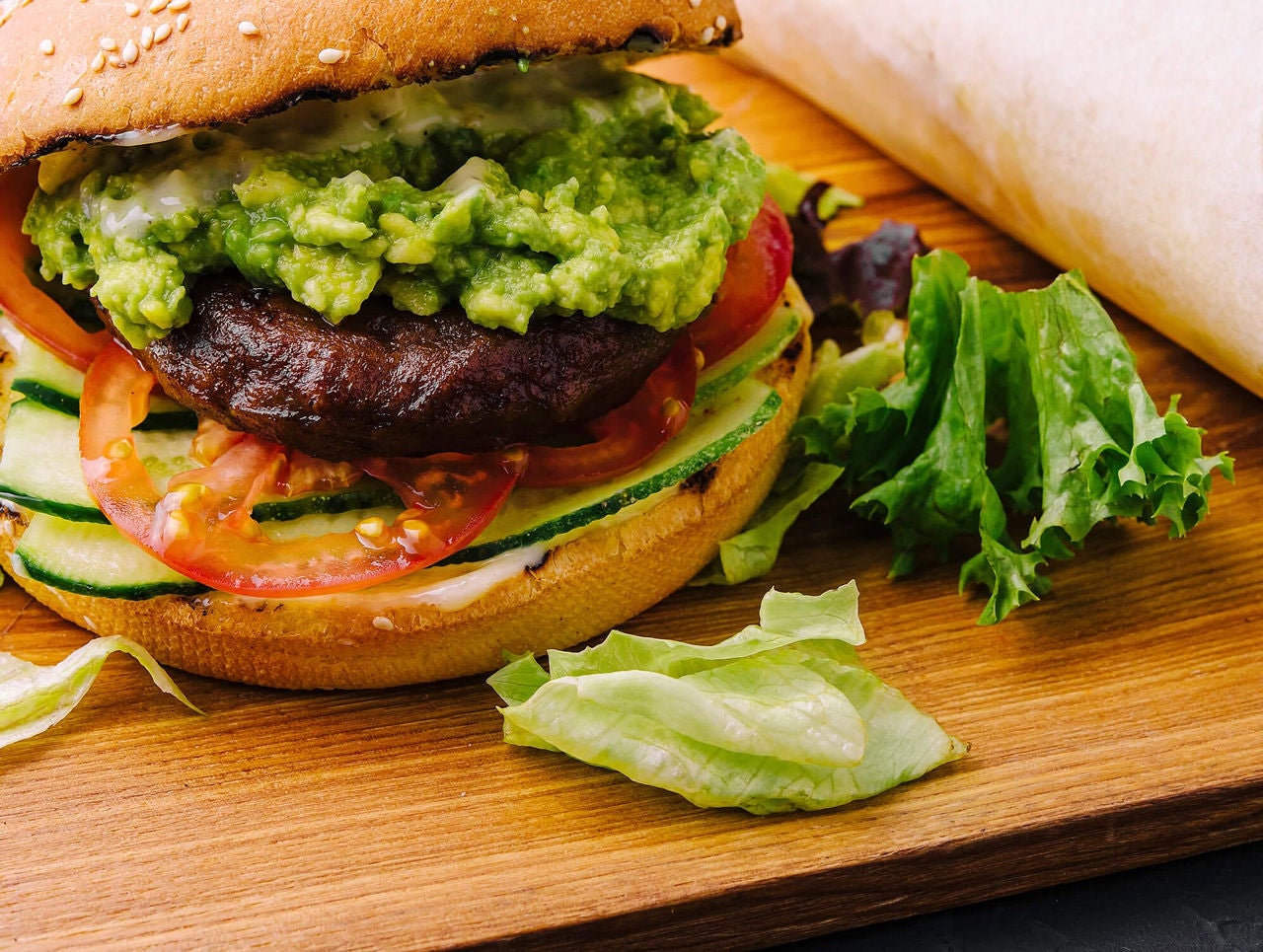 A nutritious homemade burger with fresh vegetables and guacamole, following the 'Build a better-for-you burger' guide