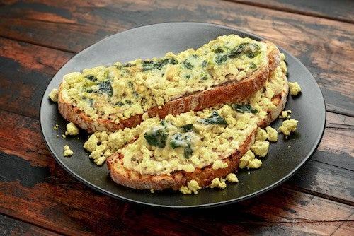 Scrambled Tofu crispy Toast with guacamole and spinach, tomato salad. Vegan vegetarian, plant based food.