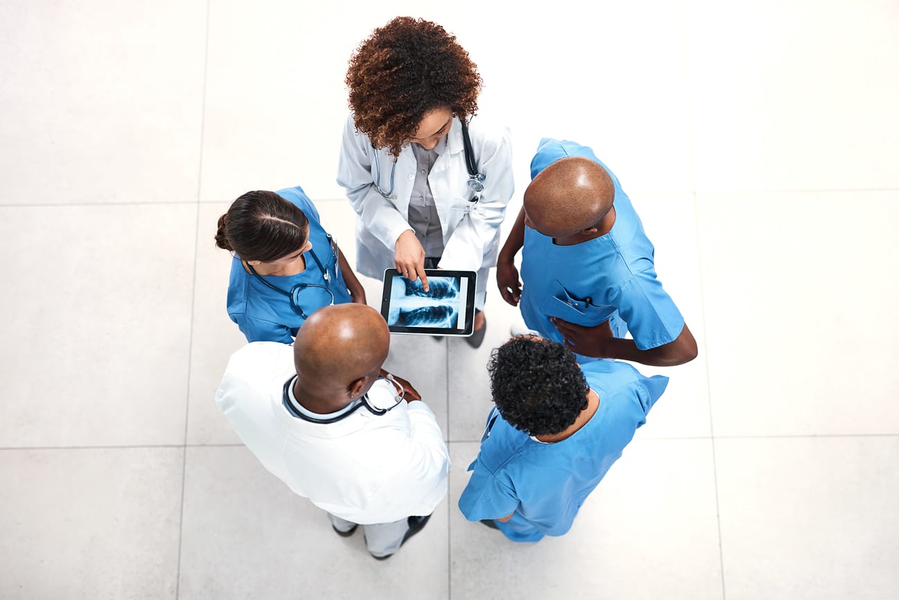 Medical team surrounding a tablet looking at an image of an x-ray