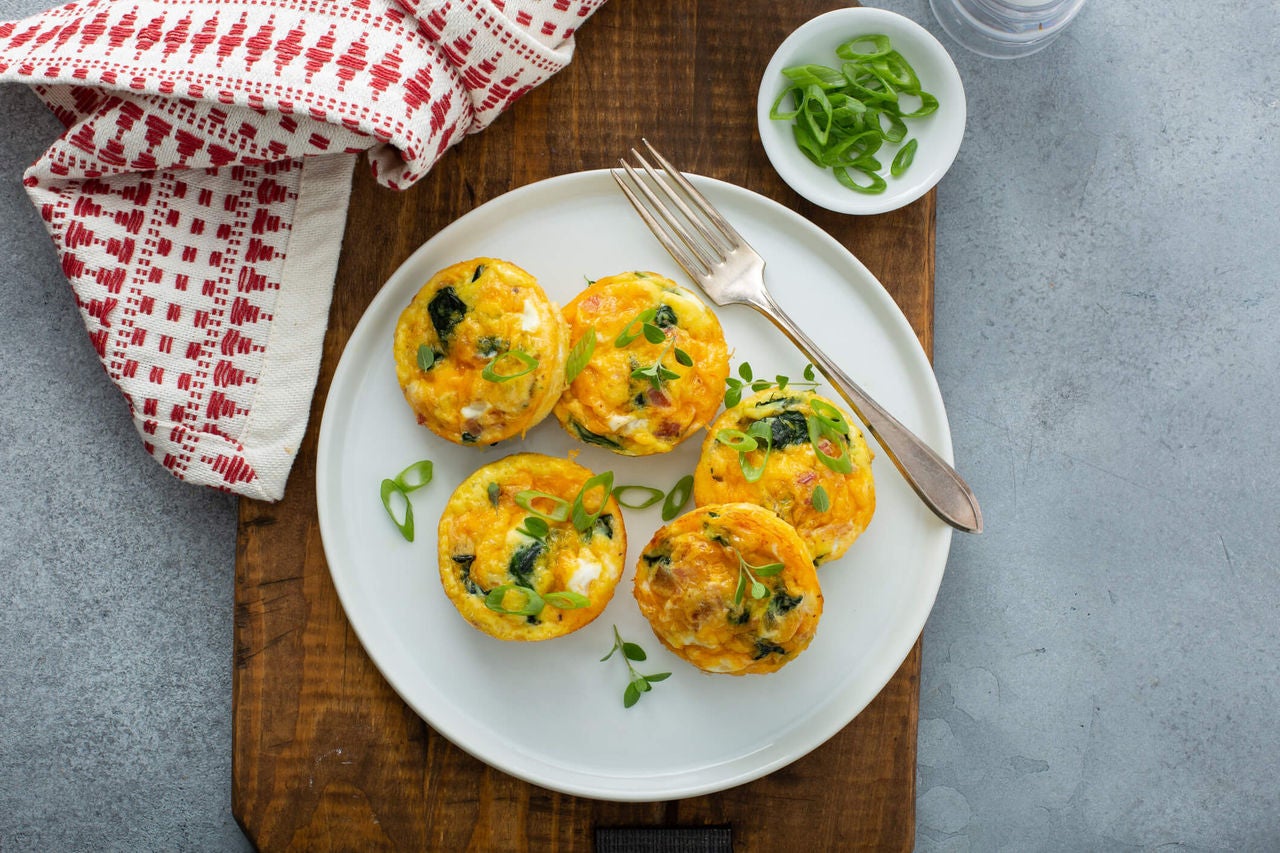 Egg muffins with greens, topped with chives on a plate.