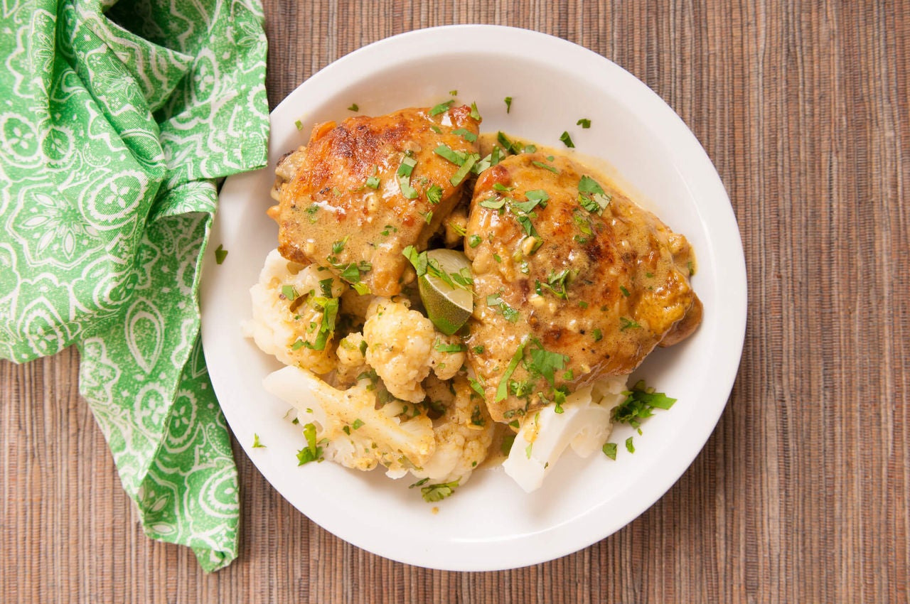 Plate with chicken thighs and cauliflower with seasonings and herbs.