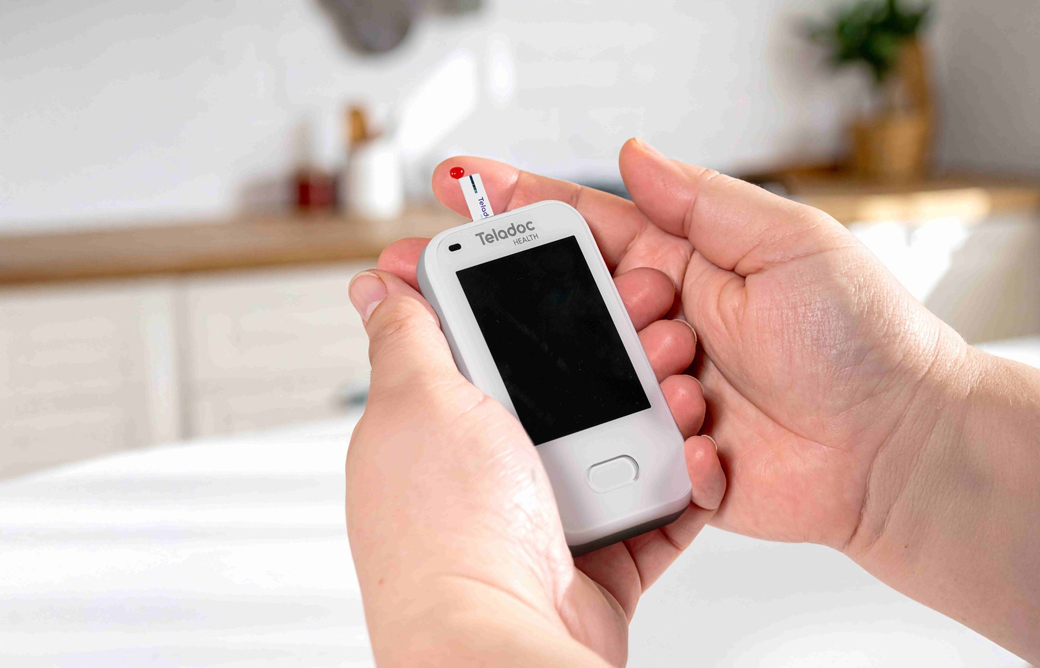 A person applying a blood test strip to a prick of blood on a finger.