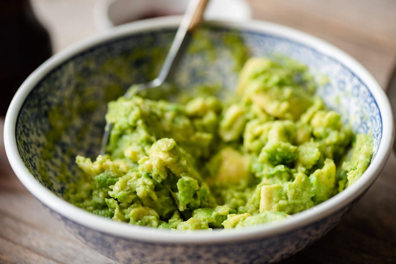  Bowl of mashed avocados with fork. 