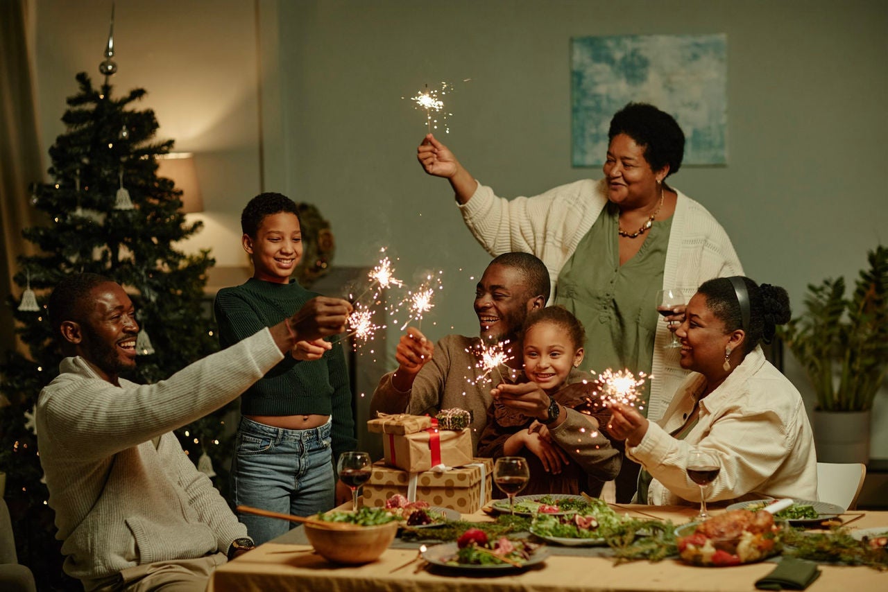 Family sitting around a set table with sparklers and presents.