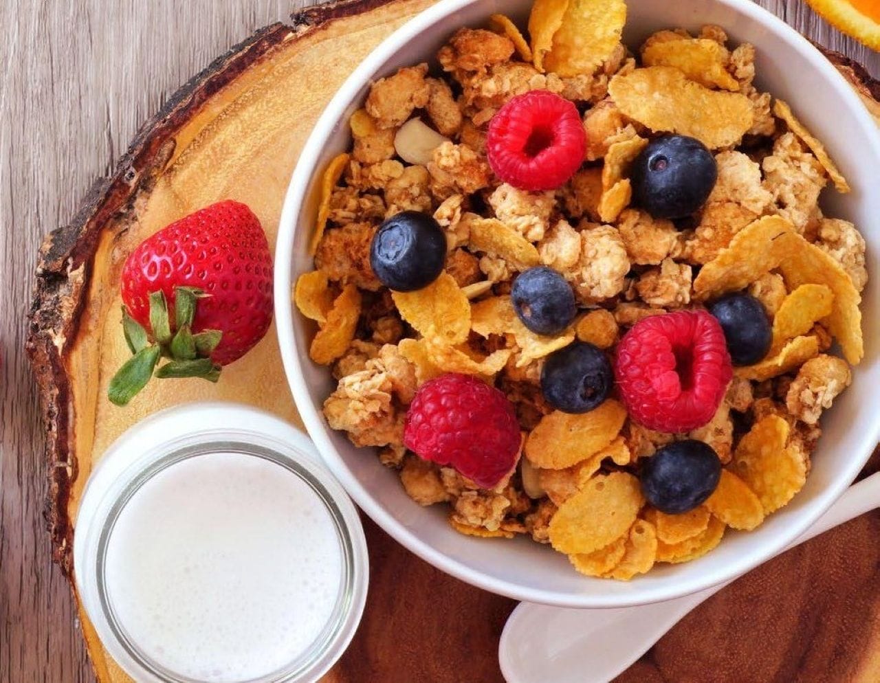 Bowl of cereal with fruit on top and a glass of milk