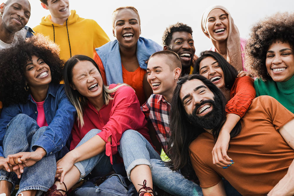 A diverse group of people is gathered together, laughing and smiling in a joyful, candid moment