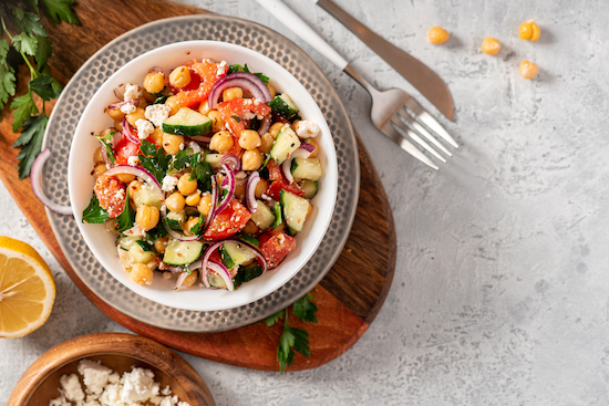 Chopped chickpea salad in bowlon wood cutting board