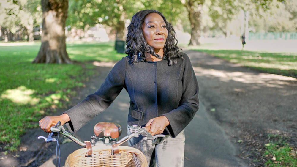 woman walking in the park with her bicycle
